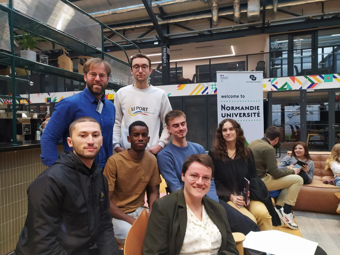Frédéric Desclercs et des étudiants entrepreneurs réunis au MoHo devant le panneau Normandie Université