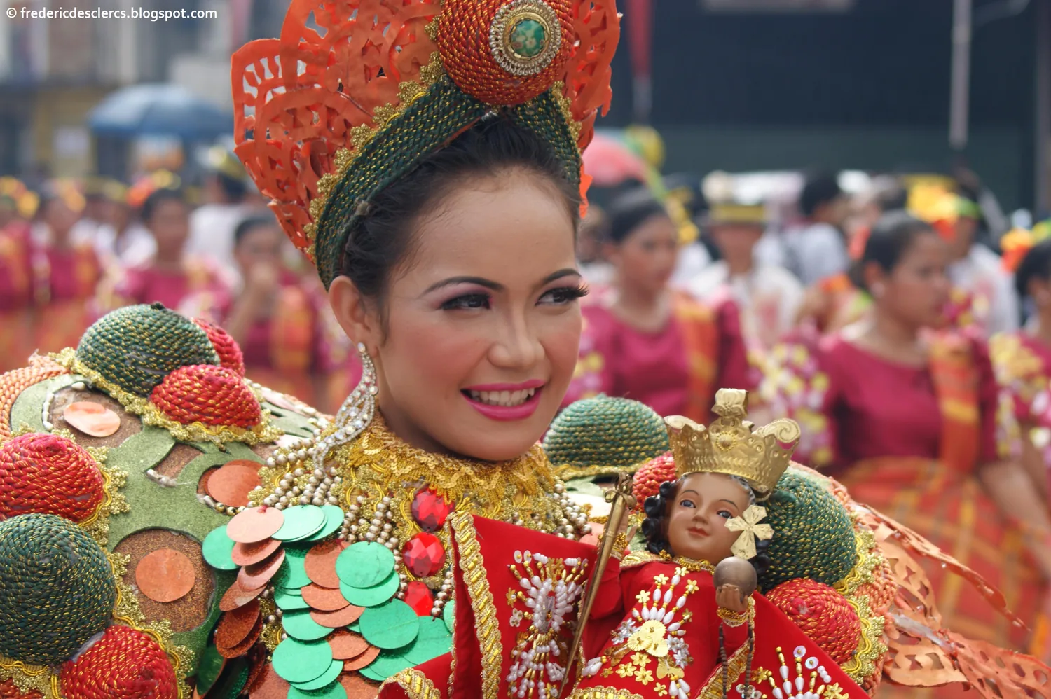 Danseuse du festival Sinulog en costume de parade tenant une statuette du Santo Niño